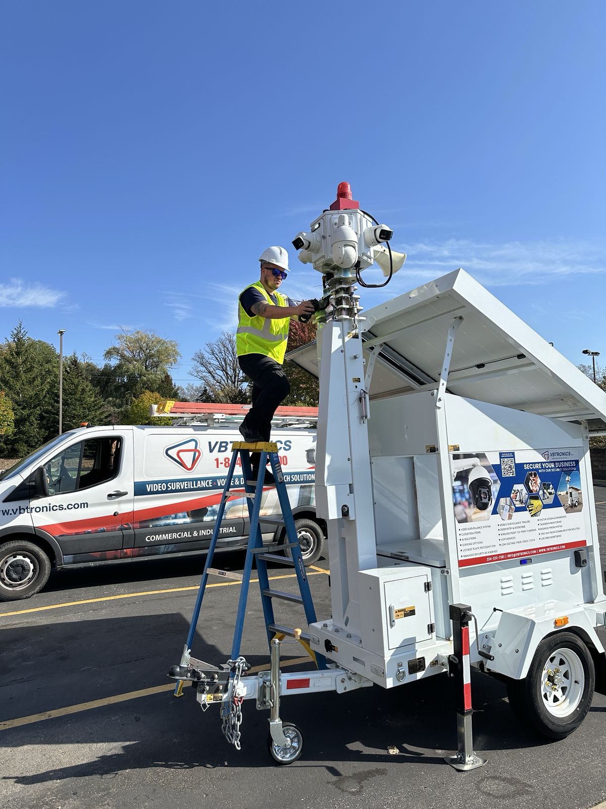 VBTronics technician servicing the camera mast of a mobile security trailer in a parking lot