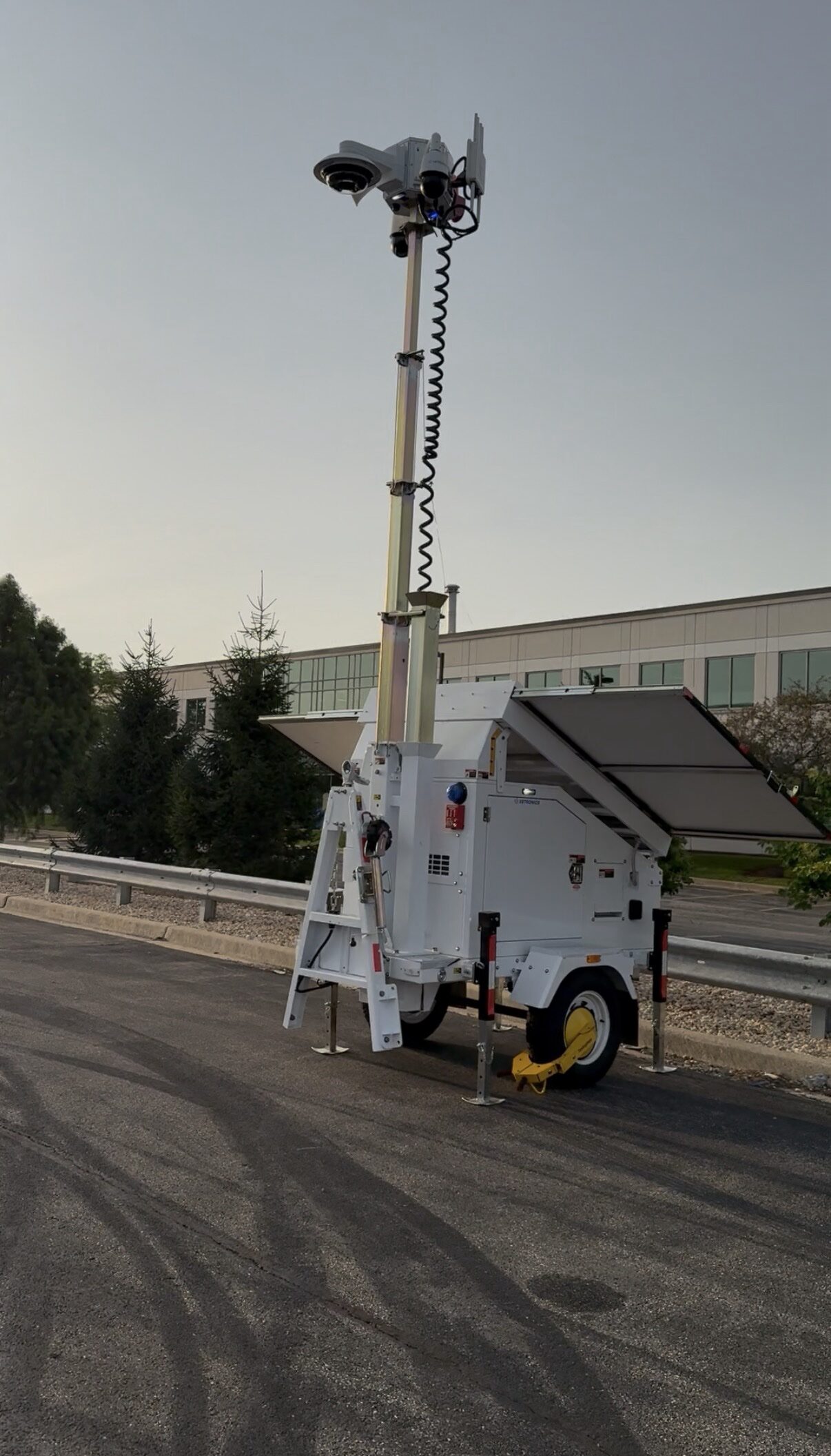 Complete Security Rental trailer deployed at a site with its camera mast raised and solar panels open